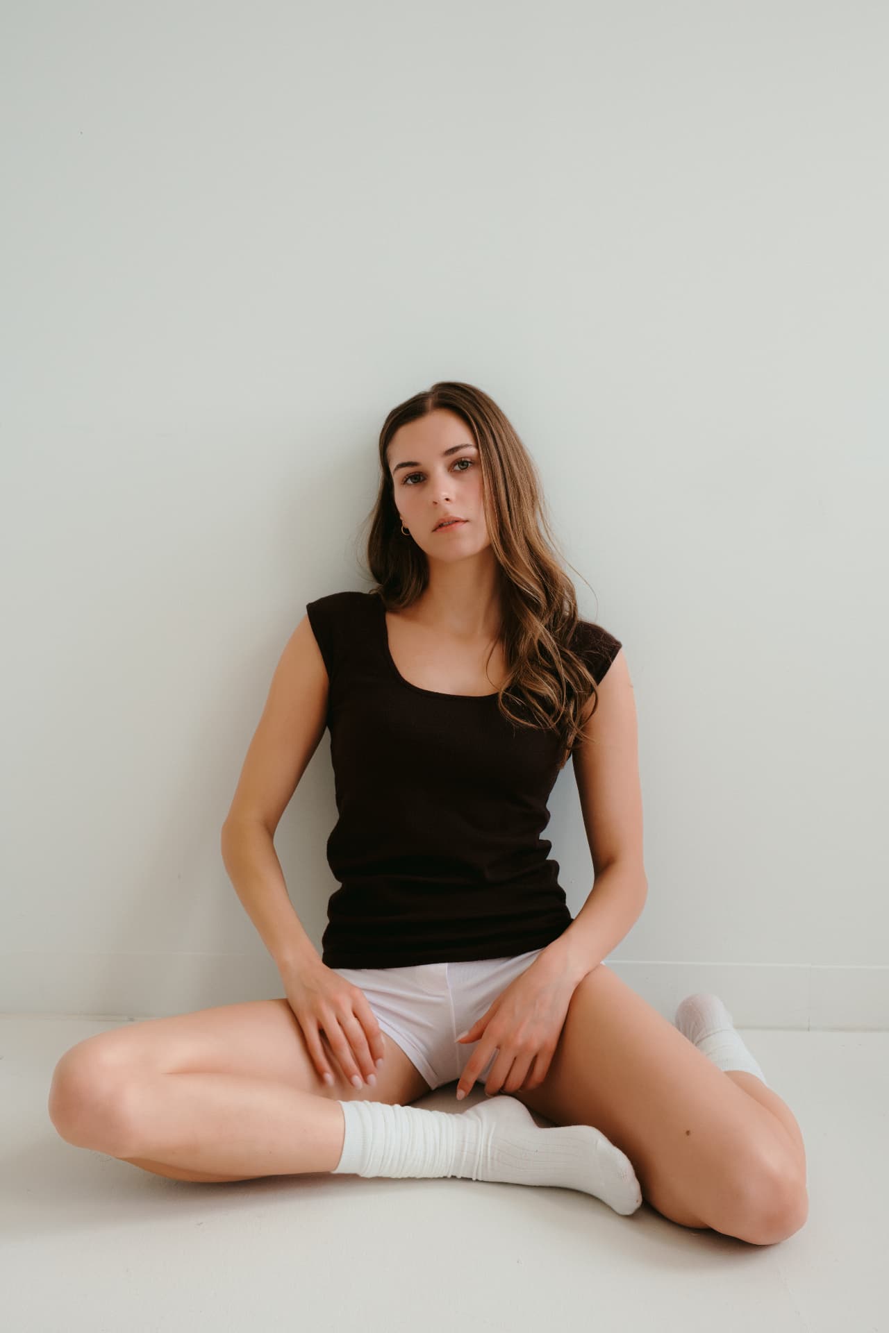 Seated floor portrait against a white wall