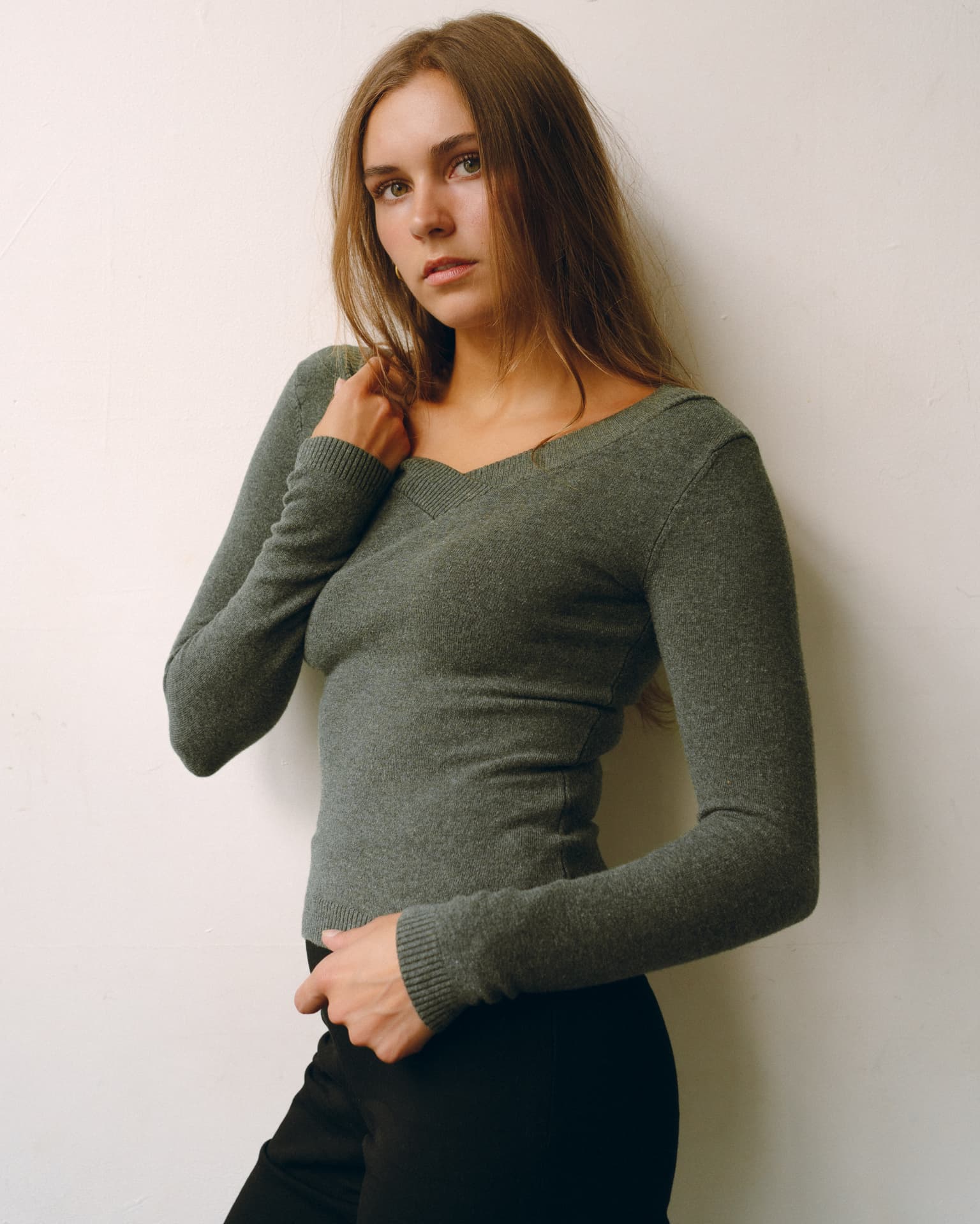 Cameron MacDonald leaning against a studio wall in a green knit top