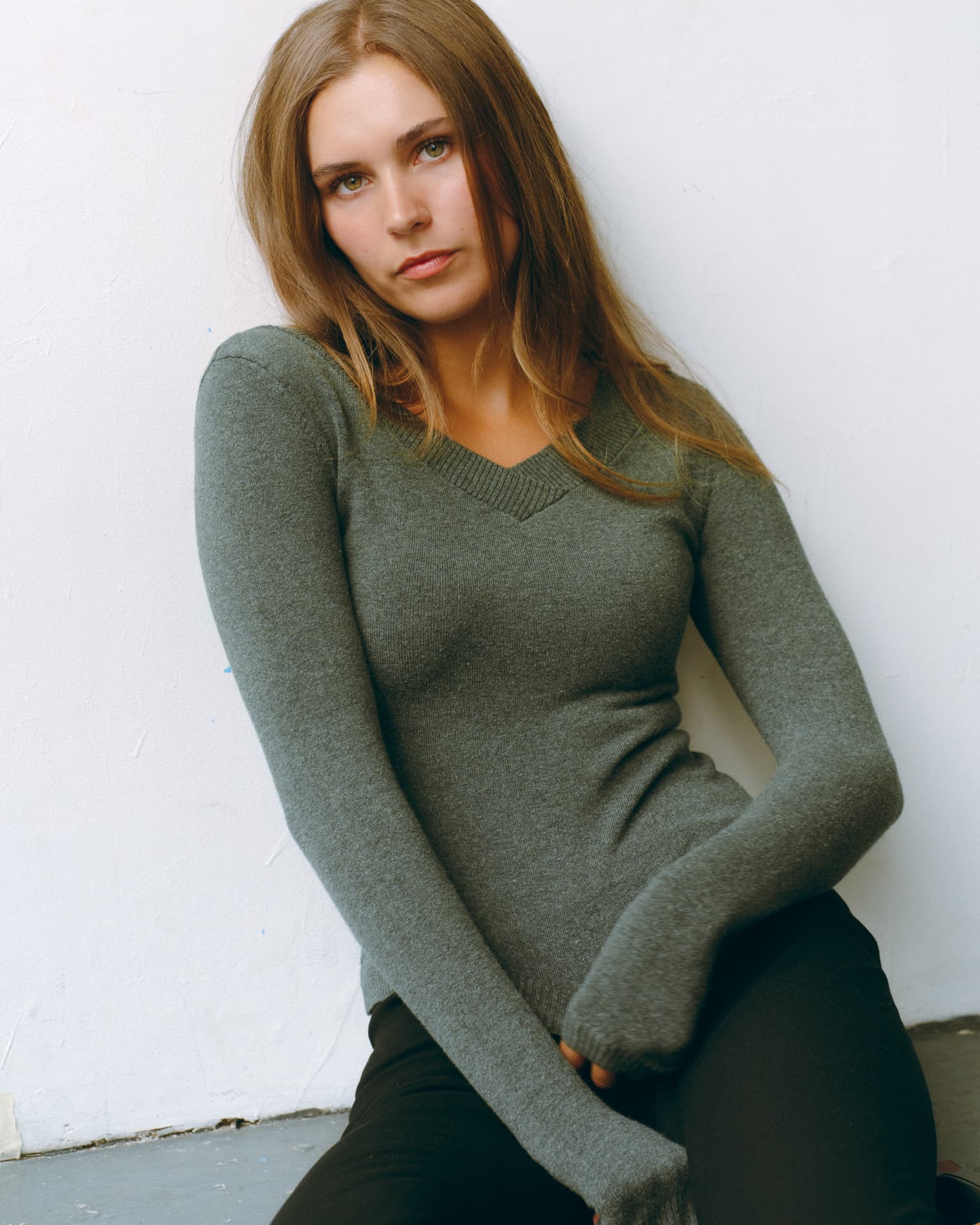 Seated studio portrait in a green v-neck knit